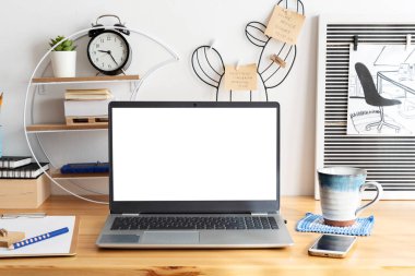 Boş monitörlü dizüstü bilgisayar ve ofis masasında bir kupa kahve. İnternette çalışırken evde çalışmak için yaratıcı bir araç olarak ahşap masa. İş ve Teknoloji.