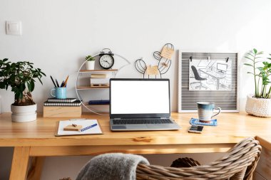 Boş monitörlü dizüstü bilgisayar ve ofis masasında bir kupa kahve. İnternette çalışırken evde çalışmak için yaratıcı bir araç olarak ahşap masa. İş ve Teknoloji.