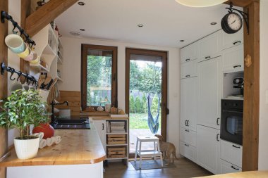 Beyaz ahşap mobilyalar ve kırsal ayrıntı ile klasik tarzda modern mutfağın içi. Pencere ve ahşapla aydınlık.