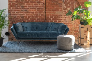 Geniş oturma odasındaki donanma koltuğu. Çatı katında, kırmızı tuğlalı duvar. Fotokopi alanı ve yerde halı var..