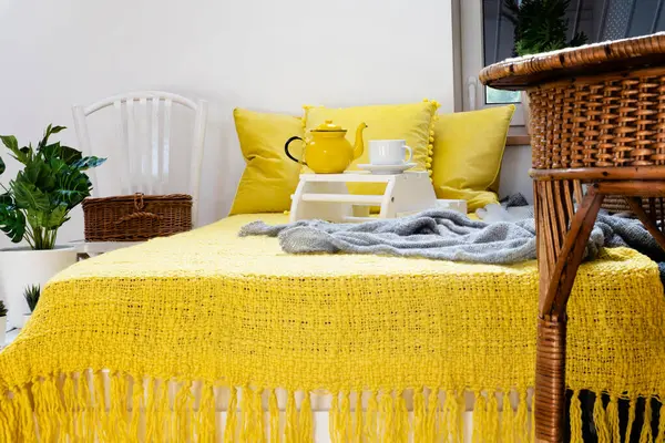 Morning with cup of coffee in bed with yellow pillows and decoration. Cozy interior of bedroom in hotel.