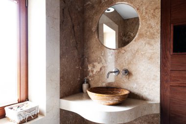 Pencereli bej mermer banyonun içi lüks. Modern lavabosu olan şık bir ev. İçerisi parlak..