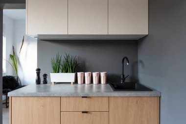 Mutfağın içinde tezgah üstü, ahşap dolap ve beyaz mobilyalar ve muslukla lavabo var. İskandinav tarzında modern yeni mutfak.