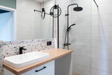 Banyosu seramik banyo lavabosu ahşap tezgahta, aynası duvarda ve modern duşu camla kaplı. Tuvaletin içi. Otel.