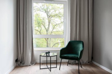 Pencere, perdeler, lamba ve ahşap zeminde boş koltuk olan odanın içinde minimalizm. Sandalyeli basit bir ev. Hiç kimse. Dikey.