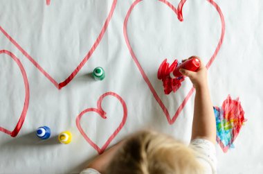 Hands of liitle child paint symbol of love in diffrent colors. Creativity and education in kindergarten.