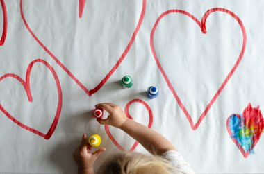 Hands of liitle child paint symbol of love in diffrent colors. Creativity and education in kindergarten.