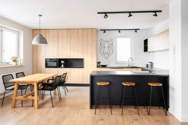 Modern interior of kitchen with kitchen island, granite kitchen island, wooden furnitureand stylish table and chairs. Spacious and luxurious space in apartment.