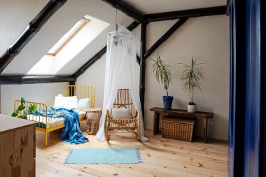 Interior of children room in the attic with yellow bed with blue bedspread and wooden floor in minimalist and style. Attic bedroom in apartment with simple decor and design. clipart