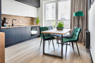 Yemek odasında yeşil sandalyeli ahşap modern masa ve ahşap zemin ve pencereli mutfak..