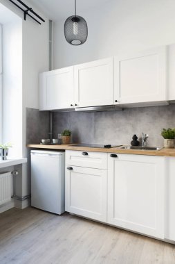 Pencereli mutfak, ahşap mobilyalar ve çatal bıçaklı tezgah. Dairede modern oda. İskandinav tasarımı. Dikey.