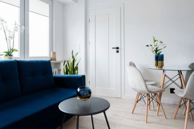 İçinde masa, sandalye ve kanepe olan bir oda. Mobilyaları, beyaz duvarı ve kapısı olan yeni bir daire. Otelin içinde lüks..