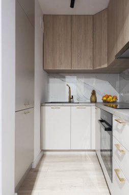 Mutfak mobilyaları, dolapları ve çekmeceleri olan modern bir mutfak. Duvarda mermer ve yeni evinde lüks bir stil. Dikey.