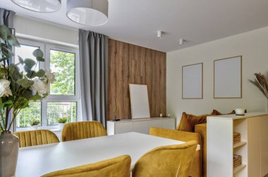 Lüks otel odası. Yemek odası, hardal desenli sandalyeler, masa, ahşap duvar, pencere ve kanepe. Yeni dairede penceresi olan modern bir iç mimari. Pankart.