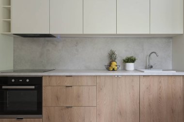 Ahşap mobilyalar ve dolaplarla modern mutfak. Mimarisi şık olan yeni bir dairede mutfak lavabosu ve ocağı var..