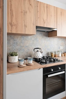 Duvarında şık fayanslar olan modern mutfak, ahşap mobilyalar, dolaplar ve tezgah ve gazlı ocak. Yeni mutfağı olan şık bir daire..