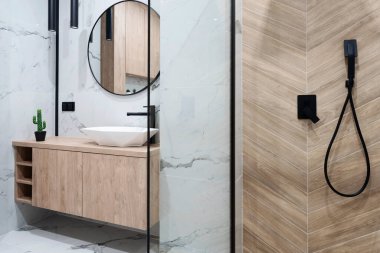 Modern banyo, cam kaplı şık bir duş ve ahşap bir dolapta seramik lavabo. Aynalar duvarda ve zarif mermer fayanslar. Çağdaş iç mekan.