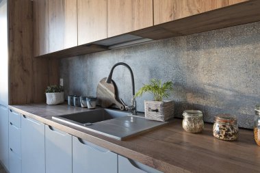 Modern mutfak içi mutfak lavabosu, şık bir musluk, ahşap tezgah, dolaplar ve duvarda fayans deseni var. Konforlu ev ve yeni daire.