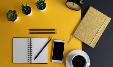 Siyah ekranlı, klavyeli, not defterli ve kahveli modern siyah ve sarı ofis masası. Kopyalama alanı olan üst görünüm, düz yatay.