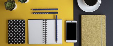 Siyah ekranlı, klavyeli, not defterli ve kahveli modern siyah ve sarı ofis masası. Kopyalama alanı olan üst görünüm, düz yatay.