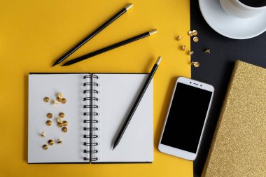 Siyah ekranlı, klavyeli, not defterli ve kahveli modern siyah ve sarı ofis masası. Kopyalama alanı olan üst görünüm, düz yatay.