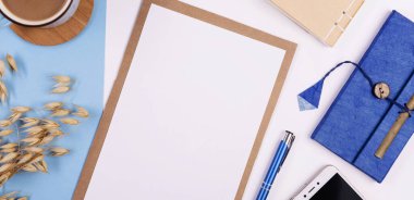 Boş çarşaflı, sulu ve mavi arka planda bir fincan kahveli şık ofis masası kavramı. Ajandada planlayıcı ve düzenleyici. Üst görünüm.