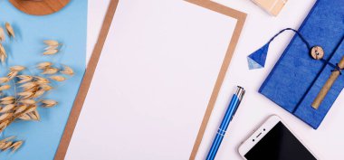 Boş çarşaflı, sulu ve mavi arka planda bir fincan kahveli şık ofis masası kavramı. Ajandada planlayıcı ve düzenleyici. Üst görünüm.