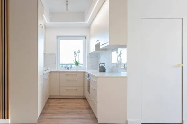 stock image Modern kitchen interior with window, counter, luxurious furniture and marble tile on the wall.. Real estate and indoors architecture.