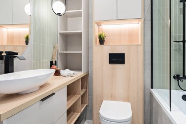 Aynalı lüks banyo, duvarında zarif yeşil fayanslar, ahşap dolapta seramik lavabo. Banyo ve banyonun modern iç mimarisi..