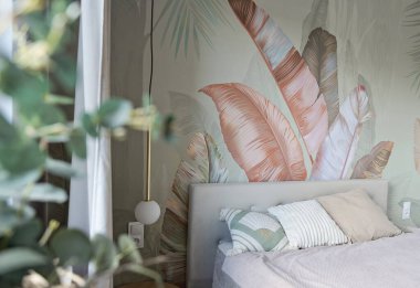 Yatak odasının modern iç mimarisi. Yastıklı, rahat bir yatak odası. Duvar kağıdında da yaprak deseni var. Tasarım evi ve konforlu ev.