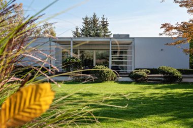 Bahçedeki ev çağdaş tarzda. Modern bina ve mimari dışında şık bir tasarım. Bahçesi, terası ve yeşili olan lüks bir yer..