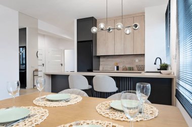 Mutfağı ahşap tezgahlı ve yemek masası boş tabak ve camla dolu modern bir yemek odası. Masanın üzerinde cam laparoskopi olan mobilyalar tasarla. Emlak.