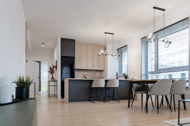 Masası, sandalyeleri, mutfağı ve ahşap zemini olan modern yemek odası. Penceresi ve gayrimenkulü olan yeni bir dairede tasarım ve minimalist mobilyalar. Kimse..