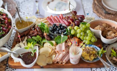 Öğle yemeğinde masada yemek için taze yemek. Soğuk tabak salata, peynir, jambon, üzüm ve zeytin. Restoranda yemek için aperatif. Pankart.