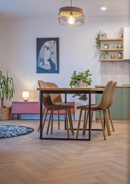 Mutfağı ve sandalyeli yemek masası olan modern bir oturma odası. Odanın içinde ahşap zemin, duvarda resim ve mobilya tasarımı. Gayrimenkul. Dikey.