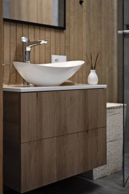 Lavabosu olan modern bir banyo. Kahverengi ve ahşap dekorlu küçük bir banyo. Seramik lavabo dolapta. İskandinav tarzı ve yaşam tarzı.