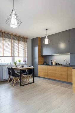 Mutfağı ve sandalyeli yemek masası olan modern bir oturma odası. Ahşap mobilyalar ve tasarım evinde zemin. Yeni dairede rahat kanepesi olan çağdaş bir oda. Dikey.