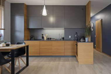 Mutfak mobilyaları, ahşap dolaplar, tezgah ve siyah sandalyeli yemek masası. Yeni evdeki lüks ve tasarım odası. Emlak.