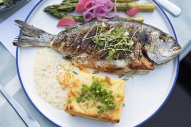Sebzeli ve soslu ızgara balık. Lezzetli sağlıklı yiyecekler ızgarada pişmeye hazır ana yemek gibi olur. Restoranda gurme dorada balığı ya da barbekü. Üst görünüm.