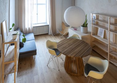 Modern ve rahat bir tasarım odası, ahşap yuvarlak masa, ahşap zemin ve lüks sandalye. Odunlu yeni daire.