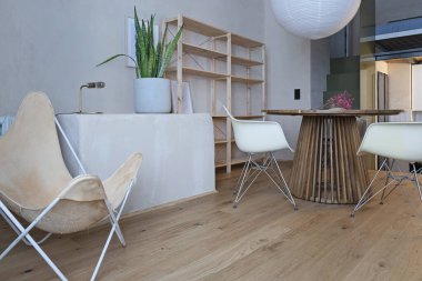 Mobilyaları, masası, sandalyesi ve koltuğu olan modern bir oturma odası. Konforlu evdeki ahşap zemin.