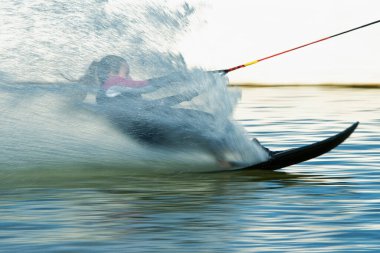 Su püskürten bir bulutun içindeki hızlı dişi wakeboardçu.