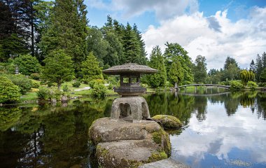 Gölet, taş pagoda ve ahşap köprülü bahçe fotoğrafçılığı; Dolar, İskoçya, İngiltere 'deki halk parkı, botanik bahçesi; yansıma; çiçekler, ağaçlar 