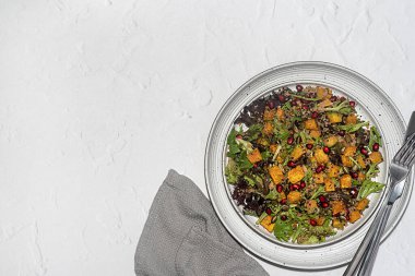 Kavrulmuş Jarrahdale balkabağı, kinoa, nar, marul, taze soğan ve balkabağı çekirdeği, sos, sağlıklı vejetaryen yemeği ve besin içeren boş bir salata fotoğrafı.