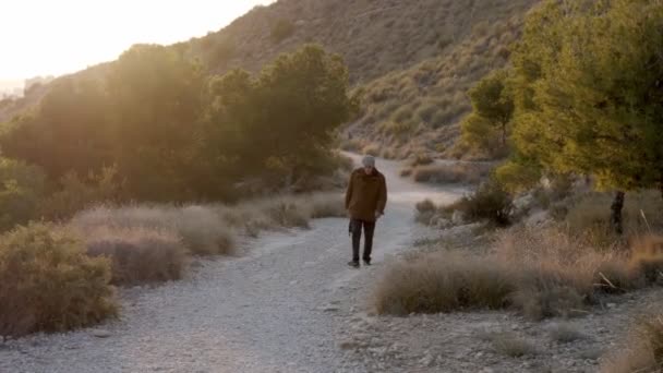 Muž Důchodu Běloch Kráčí Sám Horské Silnici Pozadí Západu Slunce — Stock video
