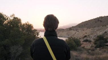 Sahil yolunda akıllı telefon kullanan genç bir kız, arka planda günbatımı dağı ve deniz. Doğanın tadını çıkarıyorum.. 