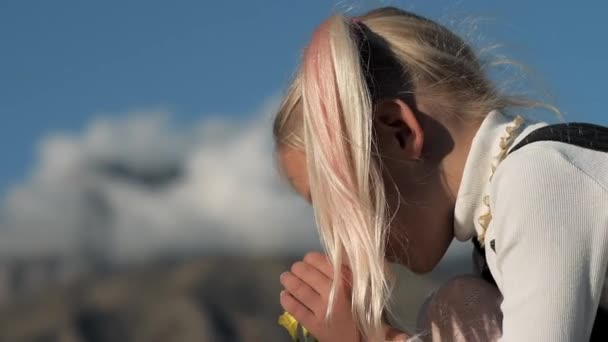 Zbliżenie Dziewczynki Wąchającej Kwiat Blondynka Kucykiem Błękitnym Niebie Górskim Tle — Wideo stockowe