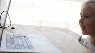 İnternette çalışan sarışın, beyaz bir çocuk. Mutlu liseli kızın elinde bilgisayarların ekranını gösteren görüntülü sohbet var. Orta boy.