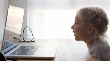 İnternette çalışan sarışın, beyaz bir çocuk. Mutlu liseli kızın elinde bilgisayarların ekranını gösteren görüntülü sohbet var. Orta boy.