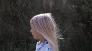 Sarışın bir kızın dağ yolunda yürüdüğünü gösteren bir fotoğraf. Orta boy.